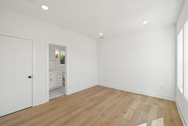 unfurnished bedroom featuring connected bathroom and light wood-type flooring