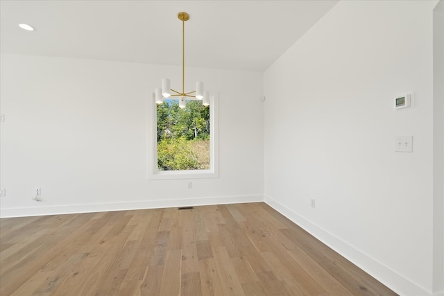 unfurnished dining area with a chandelier and light wood-type flooring