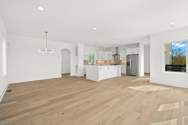 unfurnished living room featuring sink, light hardwood / wood-style flooring, and an inviting chandelier