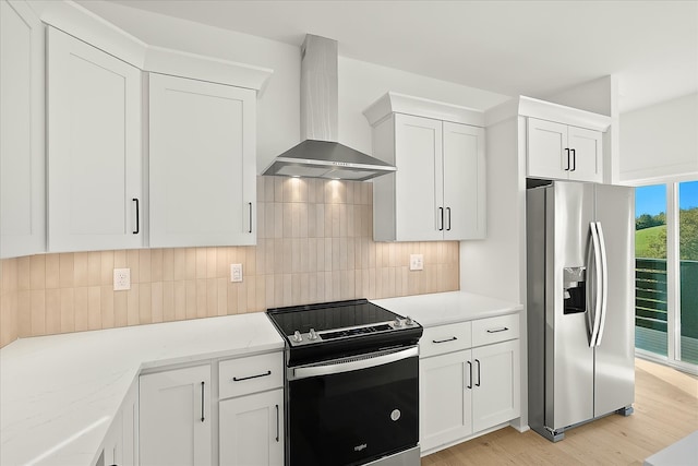 kitchen featuring white cabinets, appliances with stainless steel finishes, light stone countertops, light hardwood / wood-style floors, and wall chimney exhaust hood