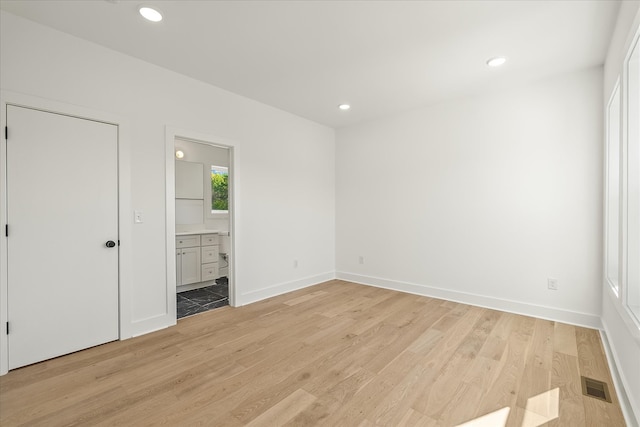 unfurnished bedroom with light wood-type flooring and ensuite bath