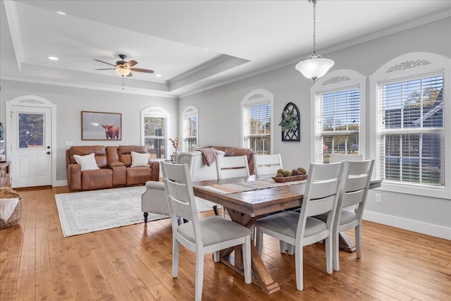 dining space with crown molding, a tray ceiling, light wood-type flooring, and ceiling fan