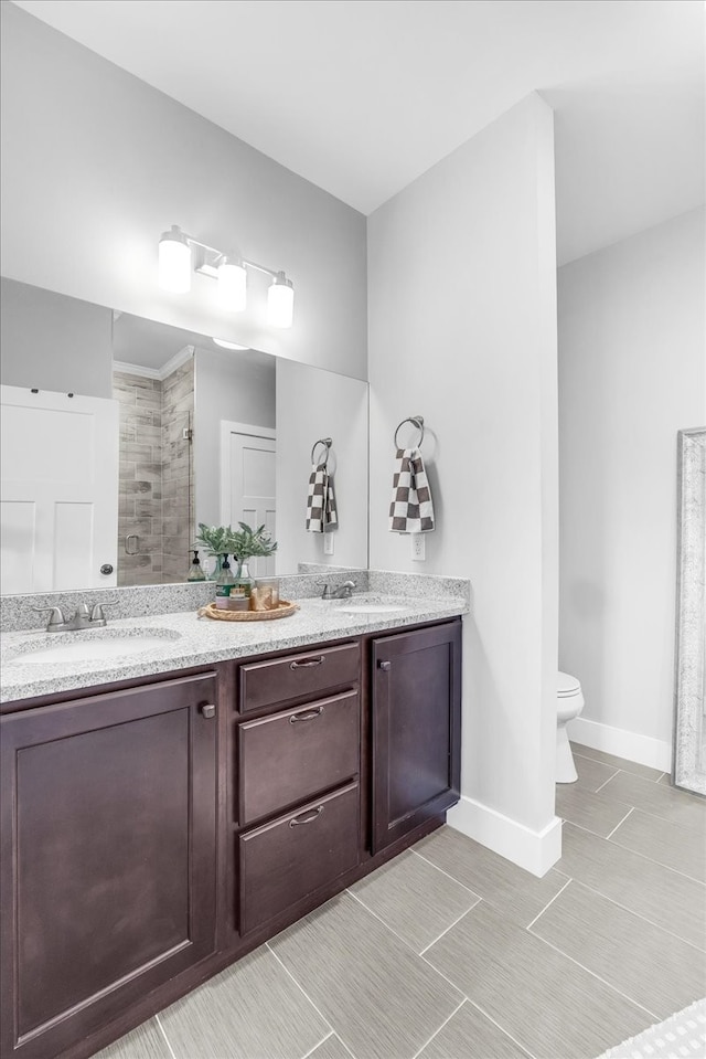 bathroom with vanity, a tile shower, toilet, and tile patterned floors