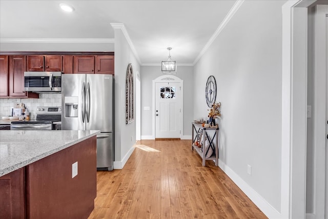 kitchen featuring stainless steel appliances, ornamental molding, decorative light fixtures, a chandelier, and light hardwood / wood-style floors