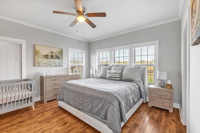 bedroom with multiple windows, ceiling fan, crown molding, and dark hardwood / wood-style flooring