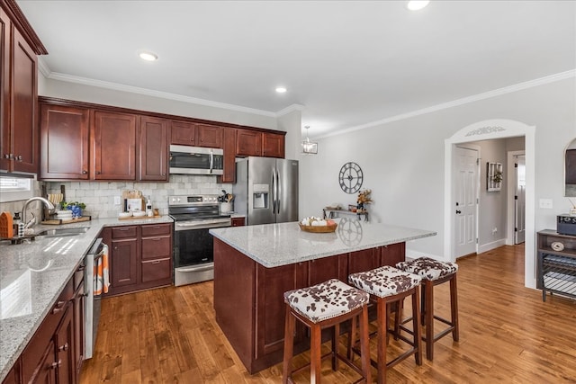 kitchen with sink, a center island, a kitchen breakfast bar, stainless steel appliances, and dark wood-type flooring