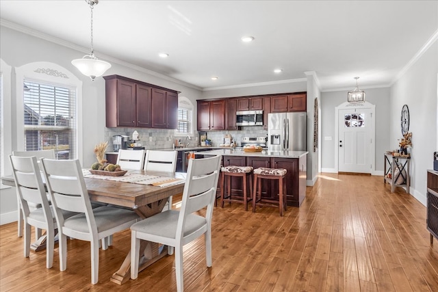 kitchen featuring appliances with stainless steel finishes, a wealth of natural light, light wood-type flooring, and hanging light fixtures