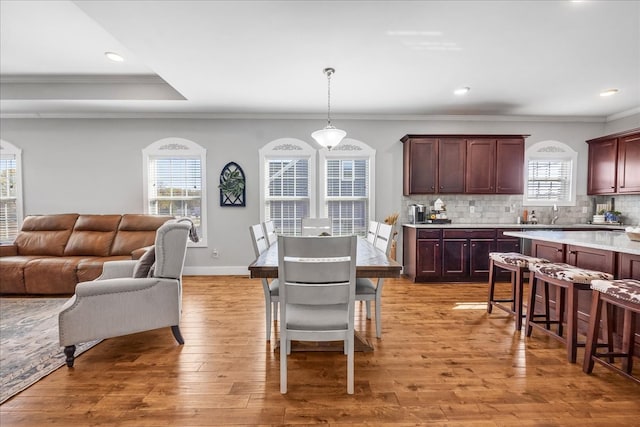 dining area featuring crown molding, light hardwood / wood-style flooring, and a healthy amount of sunlight