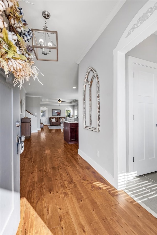 hall featuring ornamental molding, hardwood / wood-style floors, and a chandelier