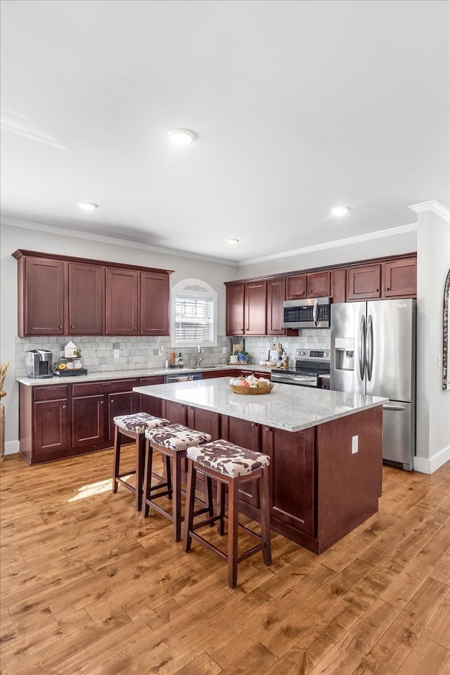 kitchen featuring a kitchen breakfast bar, appliances with stainless steel finishes, a center island, and light hardwood / wood-style floors