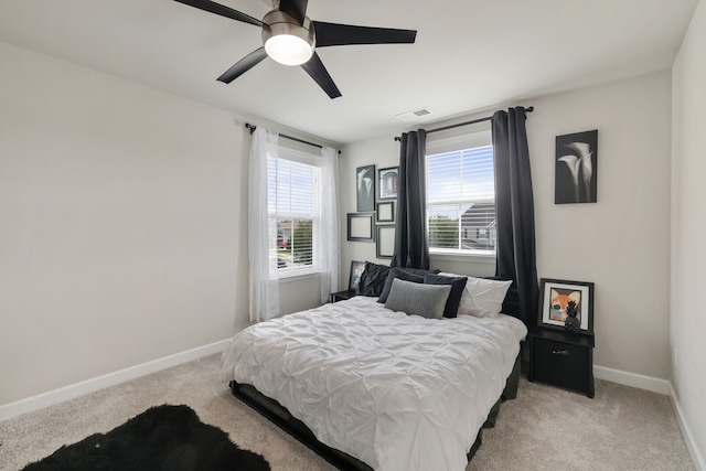 bedroom with multiple windows, light colored carpet, and ceiling fan