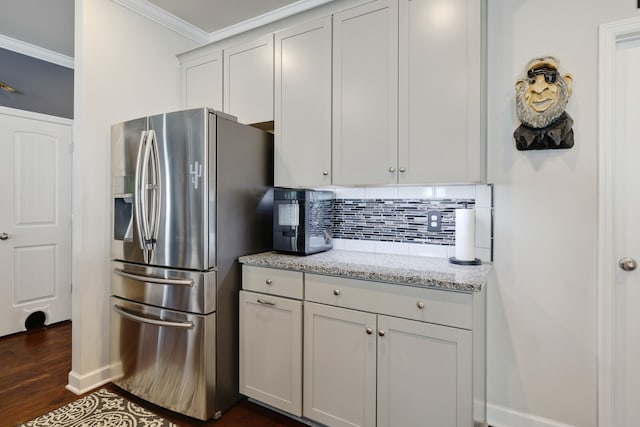 kitchen with decorative backsplash, dark hardwood / wood-style floors, crown molding, stainless steel refrigerator with ice dispenser, and light stone counters