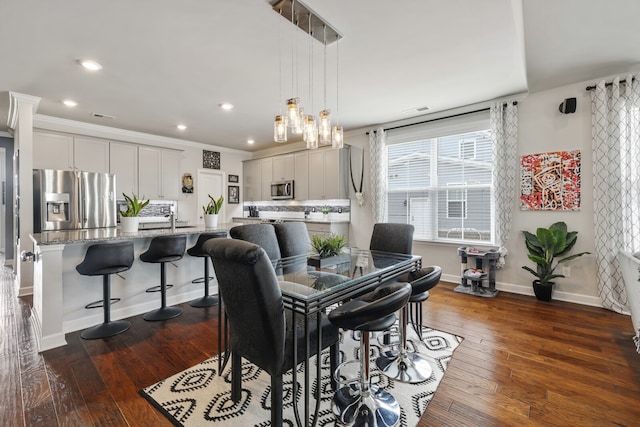 dining area with ornamental molding and dark hardwood / wood-style floors