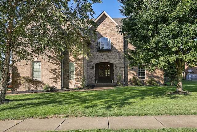 view of front of house featuring french doors, a front yard, and a balcony