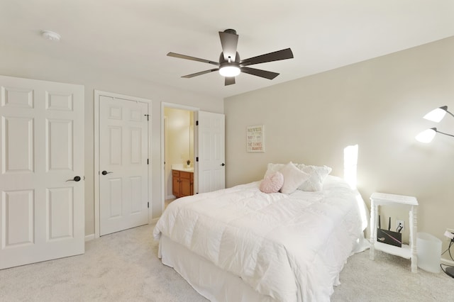 bedroom with ensuite bath, light carpet, and ceiling fan