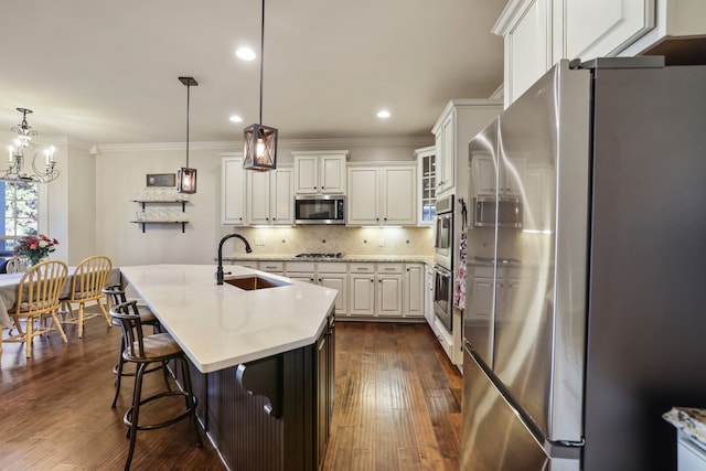 kitchen featuring dark hardwood / wood-style flooring, appliances with stainless steel finishes, white cabinetry, pendant lighting, and sink