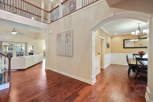 entrance foyer featuring a high ceiling, dark wood-type flooring, crown molding, and ceiling fan with notable chandelier