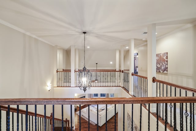 corridor with hardwood / wood-style flooring, ornamental molding, and a chandelier