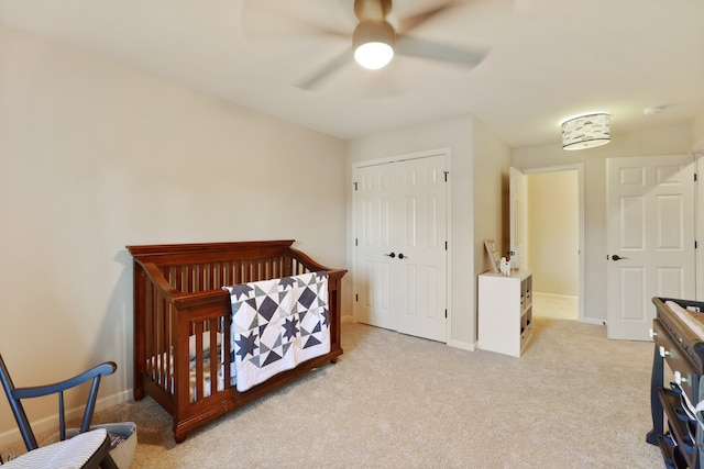 bedroom featuring light carpet, a closet, a nursery area, and ceiling fan