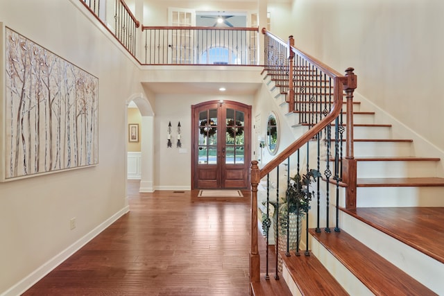 foyer entrance with french doors, wood-type flooring, and a high ceiling