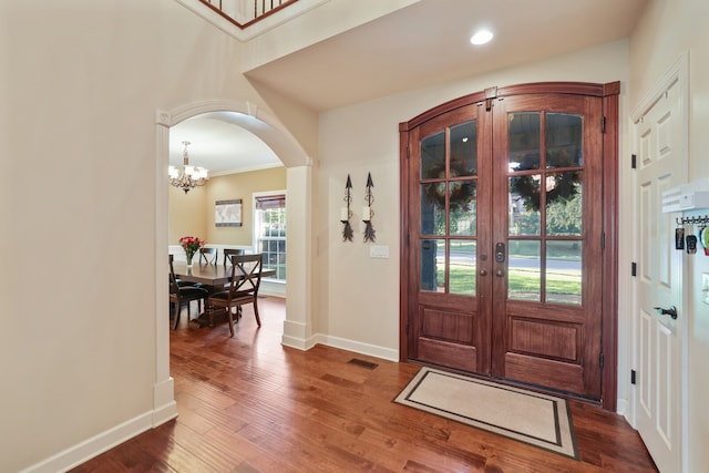 entrance foyer with ornamental molding, french doors, hardwood / wood-style flooring, and an inviting chandelier