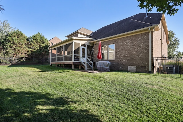 rear view of property featuring central air condition unit, a lawn, and a sunroom