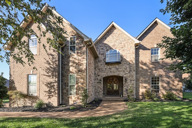 view of front of home featuring french doors, a front yard, and a balcony