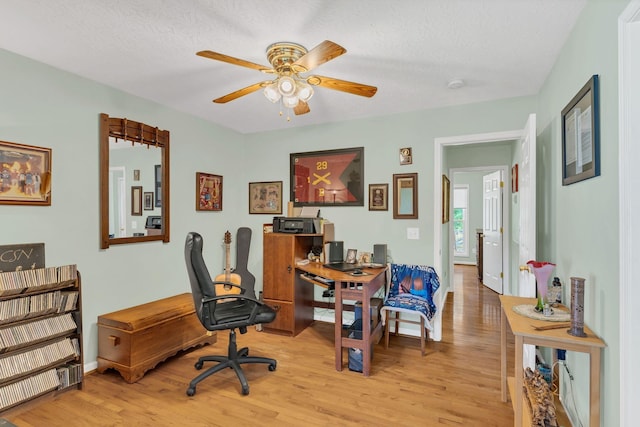 home office with ceiling fan, baseboards, a textured ceiling, and light wood-type flooring
