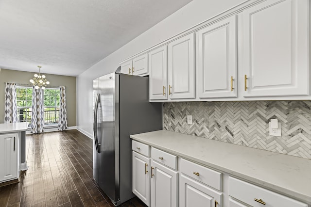 kitchen with tasteful backsplash, dark hardwood / wood-style flooring, hanging light fixtures, stainless steel fridge, and white cabinets