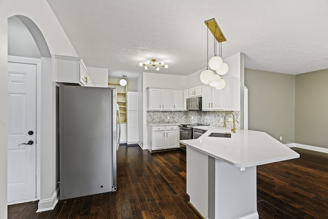 kitchen featuring kitchen peninsula, white cabinetry, stainless steel appliances, decorative light fixtures, and dark hardwood / wood-style floors