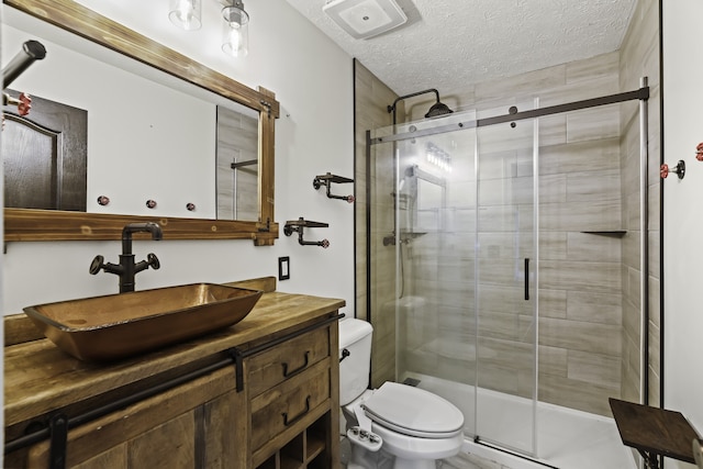 bathroom featuring a shower with door, vanity, a textured ceiling, and toilet