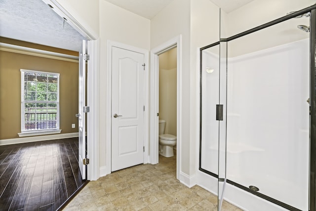 bathroom featuring a textured ceiling, wood-type flooring, toilet, and an enclosed shower