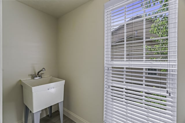 laundry area with sink, wood-type flooring, and a healthy amount of sunlight