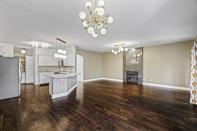 kitchen with white cabinets, tasteful backsplash, dark hardwood / wood-style flooring, stainless steel appliances, and decorative light fixtures