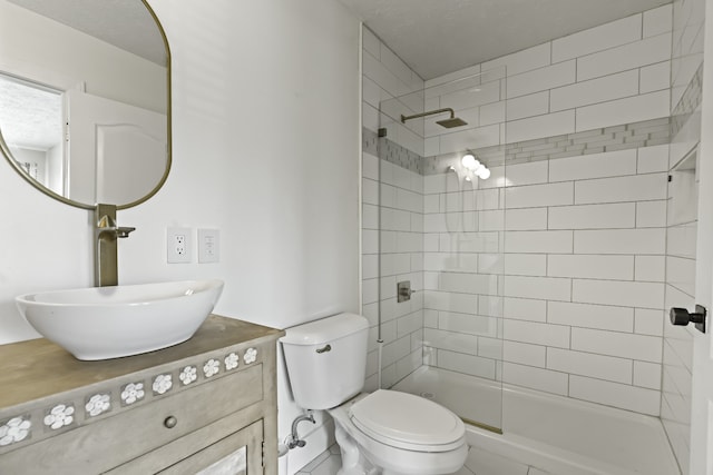 bathroom with vanity, toilet, a textured ceiling, and tiled shower