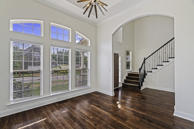 foyer entrance featuring dark wood-type flooring, ceiling fan, ornamental molding, and a high ceiling