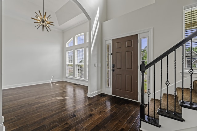 entryway featuring a towering ceiling, crown molding, an inviting chandelier, and dark hardwood / wood-style flooring