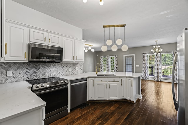 kitchen featuring kitchen peninsula, stainless steel appliances, sink, decorative light fixtures, and white cabinets