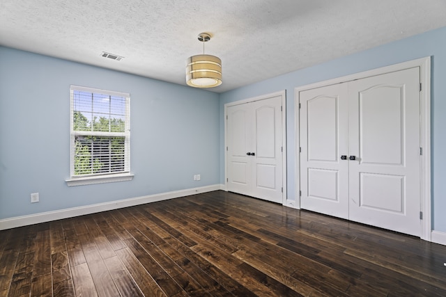 unfurnished bedroom with a textured ceiling and dark hardwood / wood-style flooring