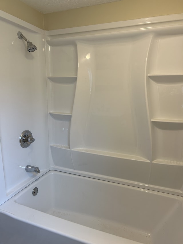 bathroom with a textured ceiling and bathing tub / shower combination