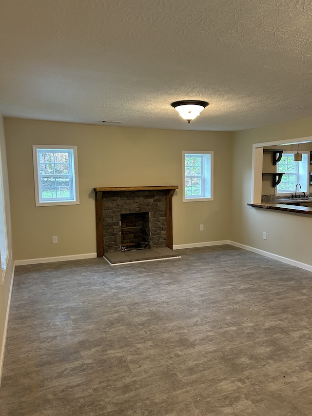 unfurnished living room featuring a textured ceiling, sink, a fireplace, and hardwood / wood-style floors