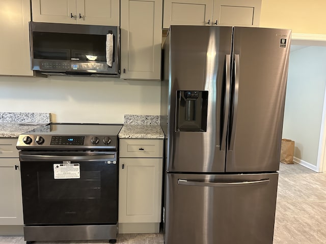 kitchen featuring appliances with stainless steel finishes, light stone countertops, and light tile patterned flooring