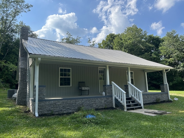 view of front of home with a porch, a front yard, and central AC unit