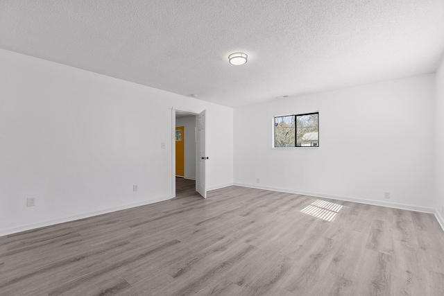 spare room featuring light hardwood / wood-style flooring and a textured ceiling