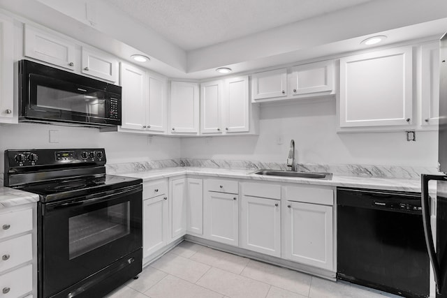 kitchen with light tile patterned flooring, black appliances, sink, and white cabinets