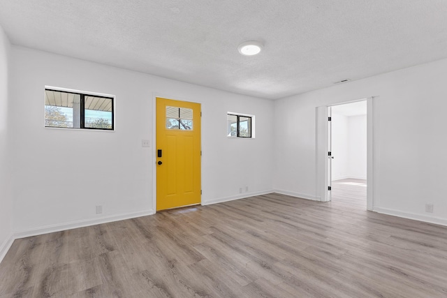 unfurnished room with a textured ceiling and light hardwood / wood-style floors