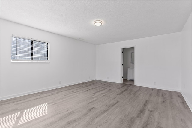 unfurnished room with a textured ceiling and light wood-type flooring