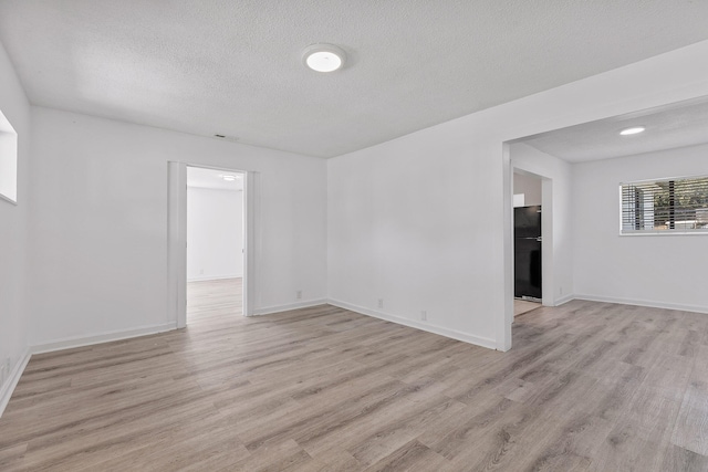 unfurnished room featuring light hardwood / wood-style floors and a textured ceiling