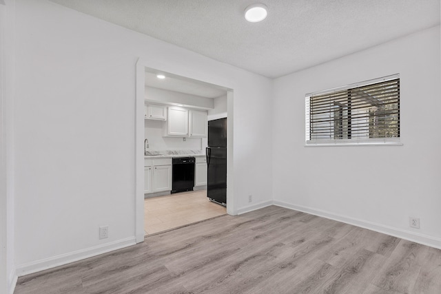 unfurnished room with sink, light hardwood / wood-style flooring, and a textured ceiling