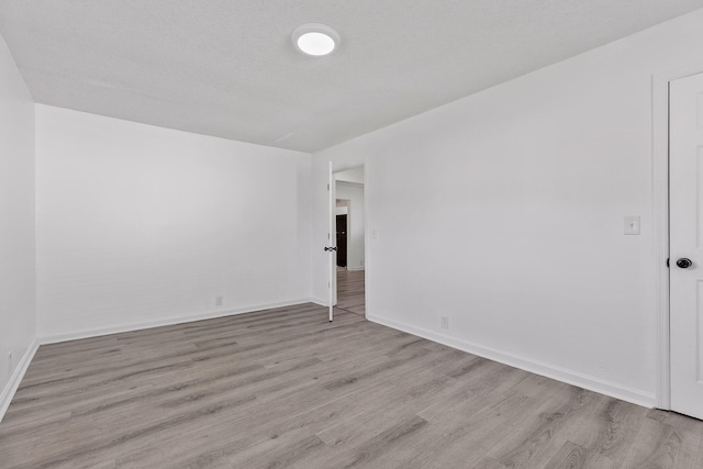 spare room featuring a textured ceiling and light wood-type flooring